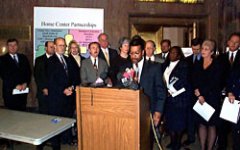 Donovan Mouton, the Mayor's Neighborhood Advocate, speaks about the problems of predatory lending as members of the Task Force on Unscrupulous Lending gather around.