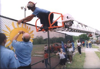 [Photo 2: Three firemen, one on an extended ladder, help put up the Art Wall.]