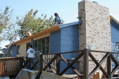 [Photo 3: World Changers volunteers work on the roof and put up a new patio door.]