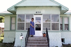 [Photo 2: New homeowner in front of the renovated house.]