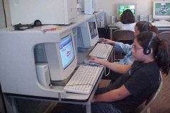 [Photo 1: Children work on the refurbished computers.]