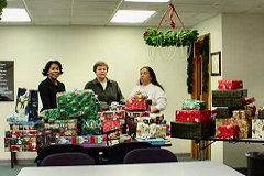 [Photo 2: Monica Izenbart, Pat Veenendal, and Pauline Sandoval put the finishing touches on gifts for the Tapia family.]