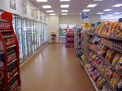 [Photo 3: An aisle in a grocery store displaying products such as soda, chips, and the freezer section]