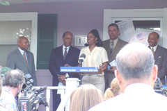 [Photo: Sharrell Fisher on the porch of her home surrounded by dignitaries]
