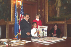 [Photo 1: A young contest winner explaining his poster]