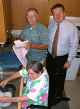 [Photo 1: Don Alexander, CHA executive director joining Ms Robbie and Mr. Tommie in their new home as she washes the dishes and her husband dries them]