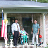 [Photo 2: Mr. Alexander, Mr. Tommie and Ms Robbie in front of the porch of their new home]