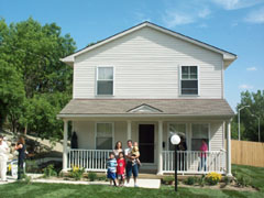 [Photo 1: Mr. and Mrs. Carballo with their three sons in front of their new home] 
