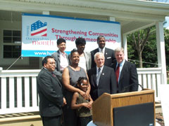 [Photo 2: Mrs. Shawana with her daughter among homeownership partners in front of her new home]