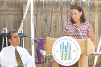 [Photo 1: D'Ann Baxter speaking from the podium on the right and Mayor Ray Martinez sitting listening to the left]
