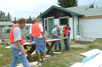 [Photo 1: A work crew installing siding on their Dollar Home]