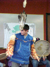 [Photo 1: A boy performing a Native American dance wearing feather hat]