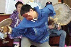 [Photo 3: A boy performing a Native American dance wearing a mask]