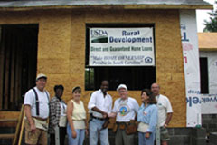 [Photo 1: William Dudley Gregorie shakes hands with Charlie Sparks while members of the Rural Development staff look-on.]