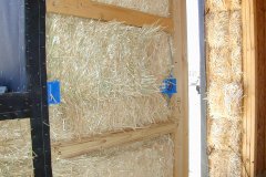 [Photo 2: Close up shot of a straw bale in the framework of an exterior wall.]