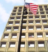 [Photo: Low angle shot of an American flag displayed before HUD Headquarters.]