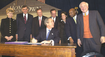 [Photo 2: President Bush signing the Act while officials standing around him watching]