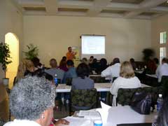 [Photo 1: View from the back of the room, showing presenters addressing the audience at a Web Clinic for HUD Partners]