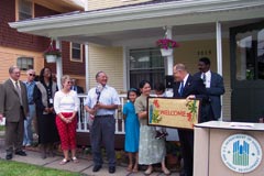 [Photo 2: HUD official presents a welcome mat to the Rodas family.]
