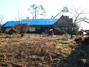 [Photo 5: Blue tarp covering the roof of home]