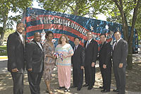 [Photo 2: New homeowners and representatives with The Homeownership Express bus in the background]