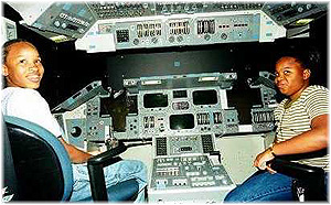 Photo: Two children sit in a shuttle flight simulator.