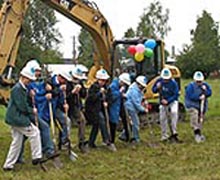 [Photo: People with hard hats and shovels breaking ground on new housing project]