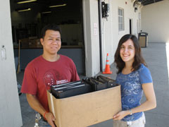 [Photo: Aliza Reisberg presents one box of notebooks to Des Moines Public Schools representative Fa Che for use by faculty and students.]