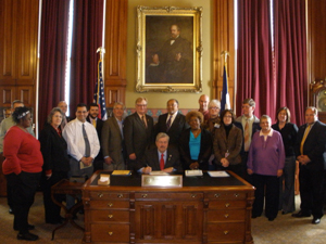 [Photo: Governor Branstad (seated) signing proclamation as 18 others watch]