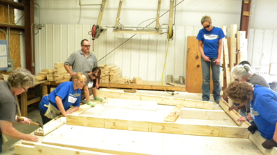 [Photo 1: Volunteers from the HUD Louisville Field Office work together to construct an exterior wall for a new Habitat home.]