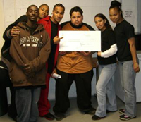 [Photo: YouthBuild students holding check]