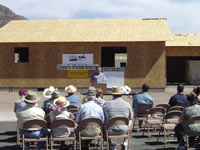 [Photo 2: Larry Smith speaking to people seated in front of partially constructed home]