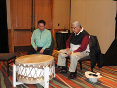[Photo 2: 2 Waterbird drum group members performing]