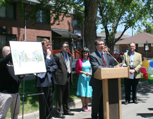 [Photo 1: Rick Garcia speaking at podium under shade of tree]