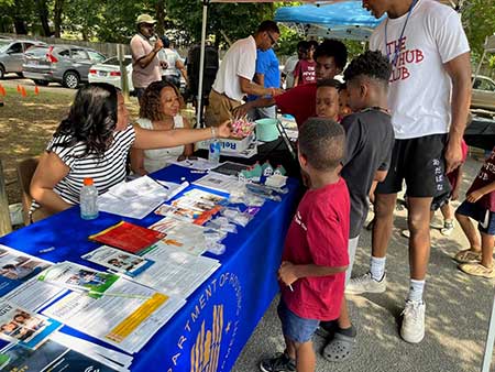 [Many children stopped by the HUD outreach table in Jackson Tennessee, where information about the Affordable Connectivity Program was made available to the Allenton Heights community residents as part of the Jackson Housing Authority's annual 2023 Family Empowerment Expo. Michelle McCarroll, Supervisory Management Analyst, and Demetra Daniel, Portfolio Management Specialist, share information about the program with parents along with treats for children attending.]