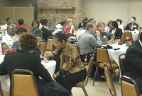 [Photo 3: Attendees seated around tables eating and talking]