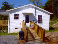 [Photo 3: Reconstructed house with access ramp]