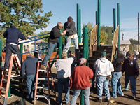 [Photo 2: Volunteers assemble playground equipment]